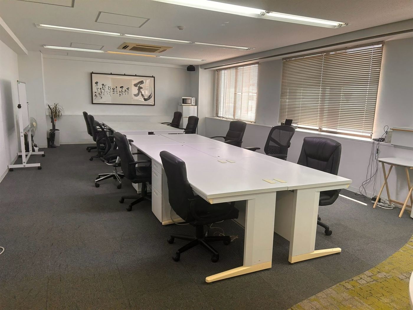 大会議室103の全景。窓から自然光が差し込む約50㎡の室内と白いデスク